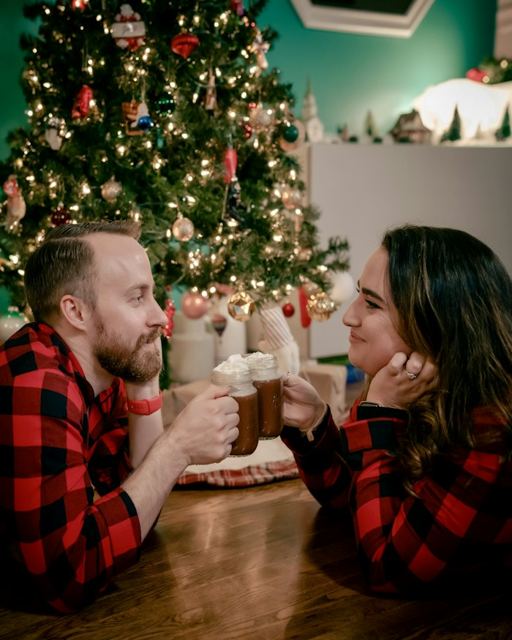 Couple with hot chocolate by a Christmas tree